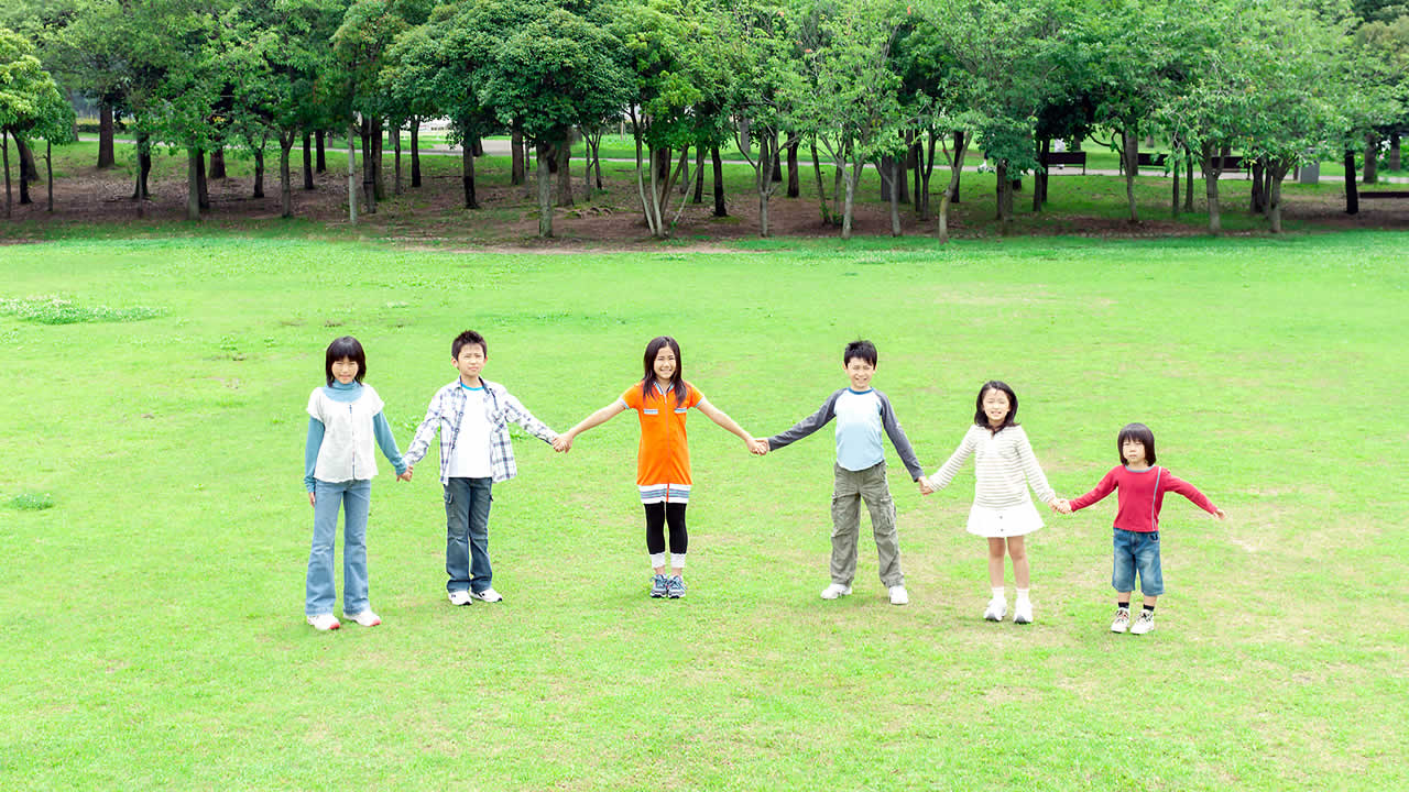芝生で手をつなぐ子供たちを撮影したイメージ
